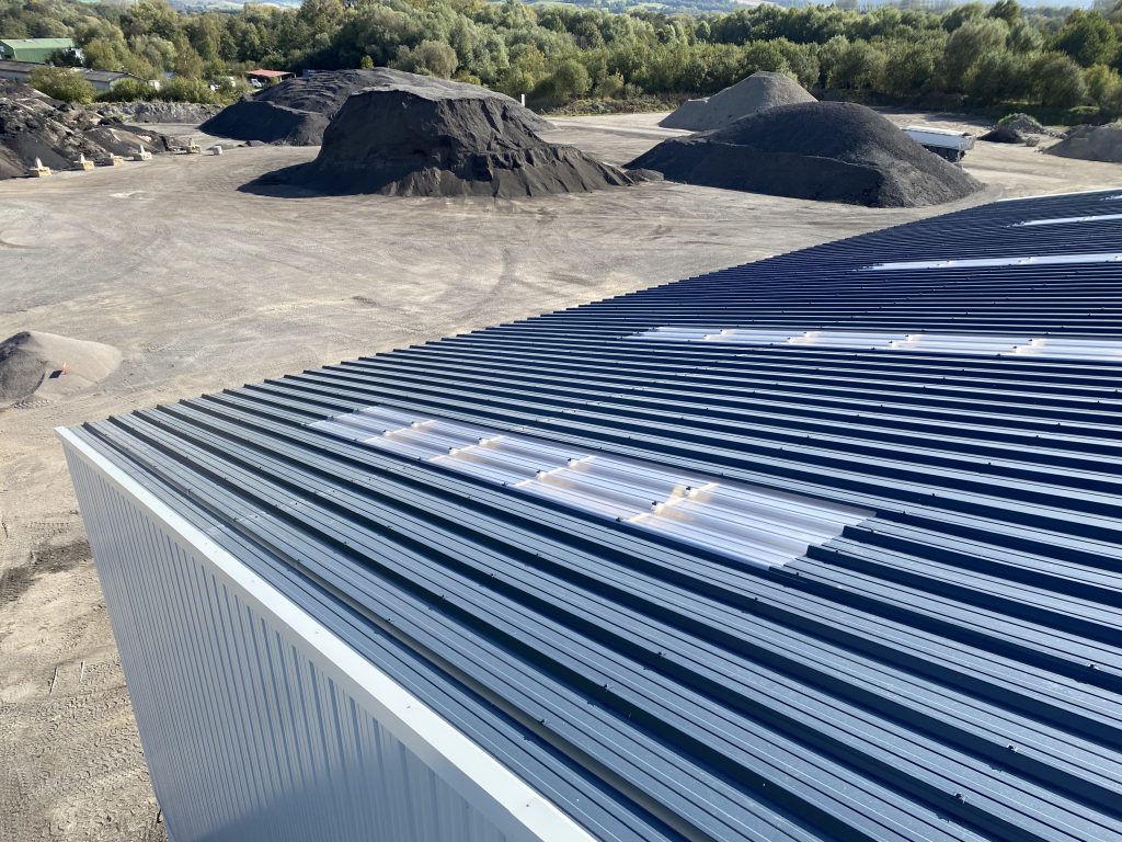 Couverture de bâtiment industriel en bac acier sec nervuré gris anthracite, intégrant des plaques translucides pour l'éclairage naturel, réalisée par Constructions Boulay, spécialiste en couverture industrielle en Normandie.