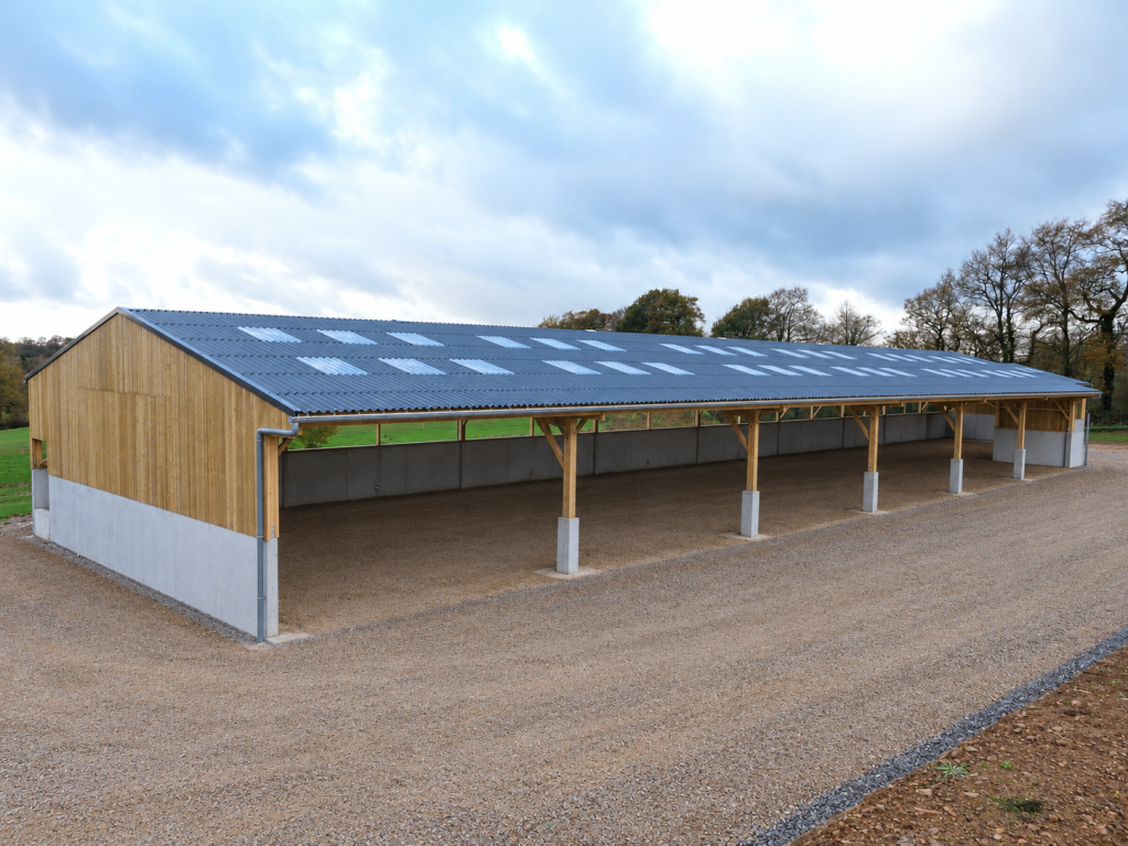 Couverture de bâtiment agricole en plaques fibres-ciment ondulées avec intégration de plaques translucides pour l'éclairage naturel, réalisée par Constructions Boulay, spécialiste en couverture agricole en Normandie.